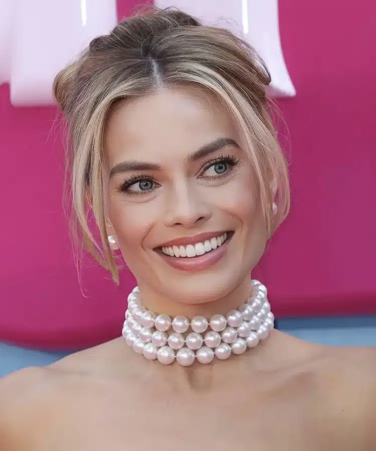 “Margot Robbie with joyful expression and visible upper dentition.”