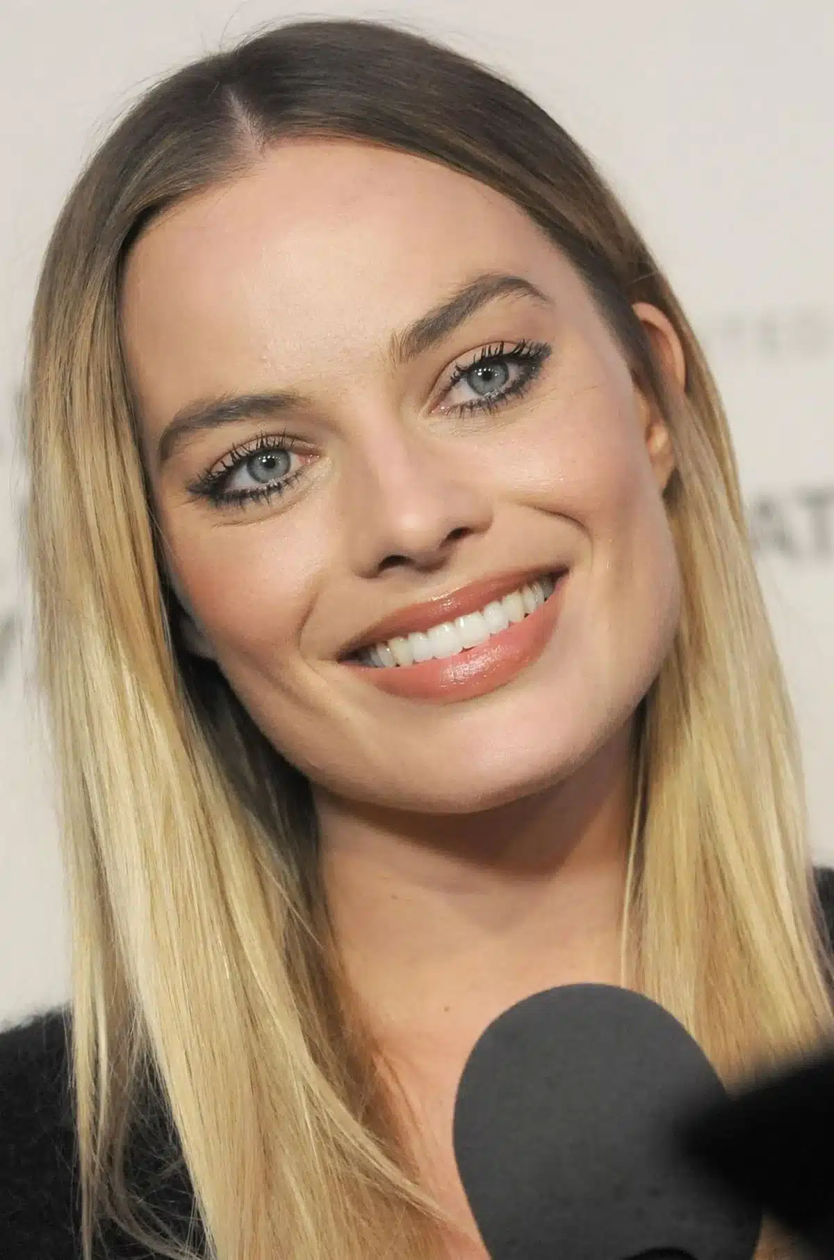“Margot Robbie laughing with expressive lip lift and visible smile arc.”
