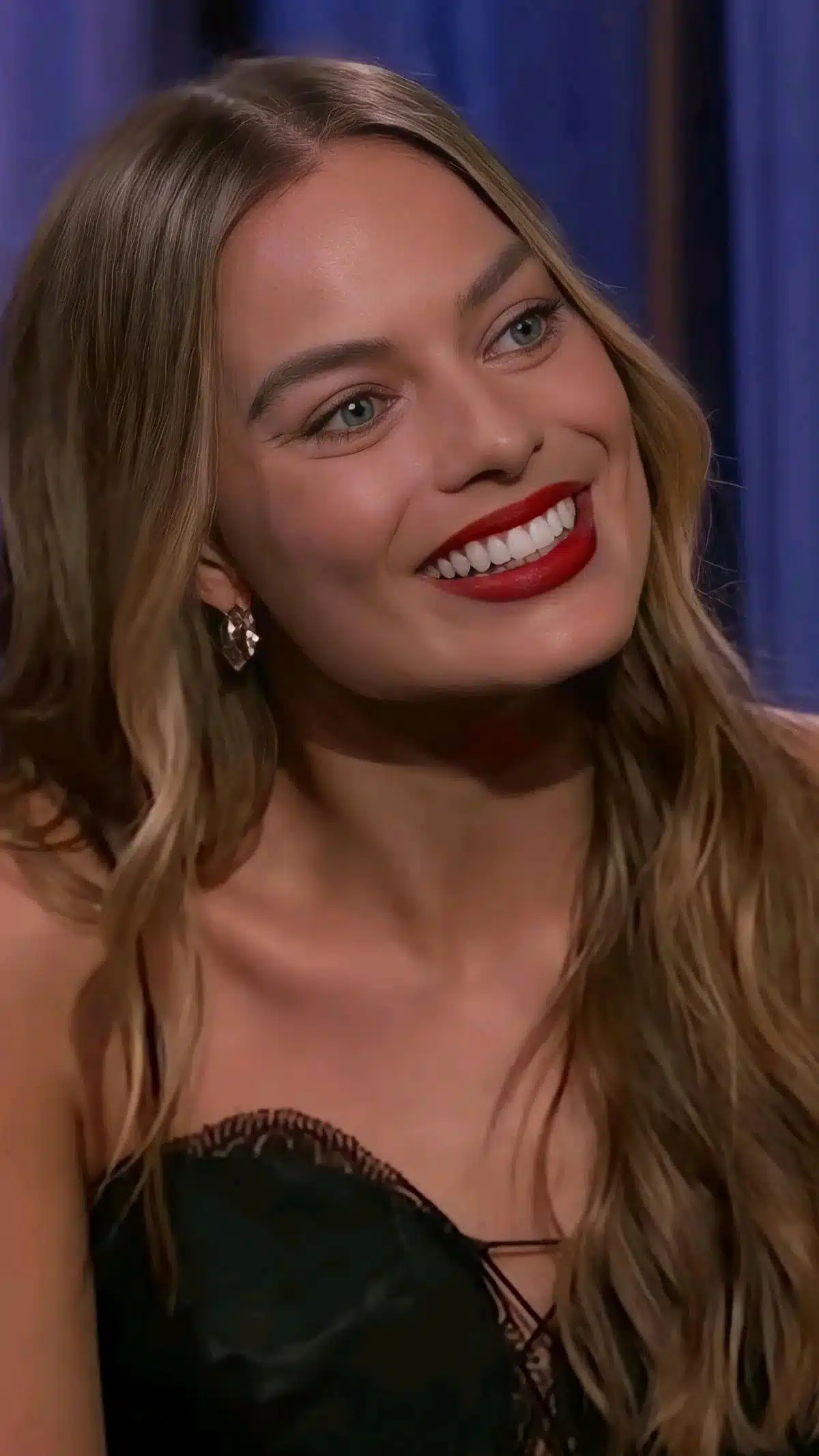 “Margot Robbie smiling in profile showing natural tooth proportion.”