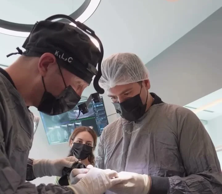 A surgeon wearing a headlamp and surgical loupes operating with a team at the Istanbul practice