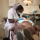 Diş hekimi tedavi koltuğunda hastanın ağzını tedavi ediyor, tepede klinik lambası