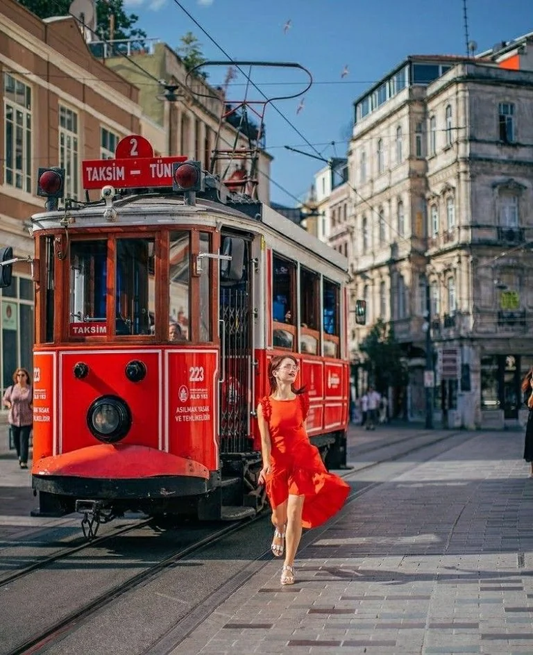 Woman in a red dress walking near the historic Taksim tram