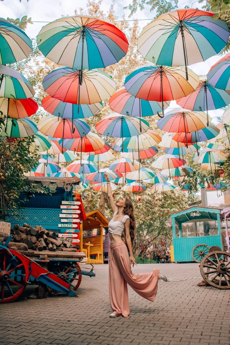 Woman standing beneath colorful umbrellas in an Istanbul courtyard