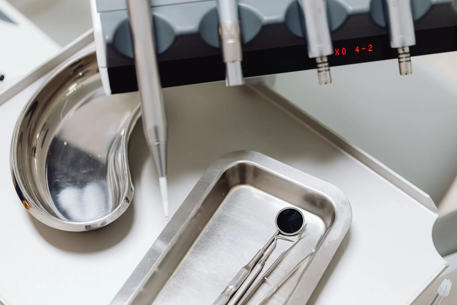 Sterilised dental instruments arranged on a clean tray beside a treatment unit