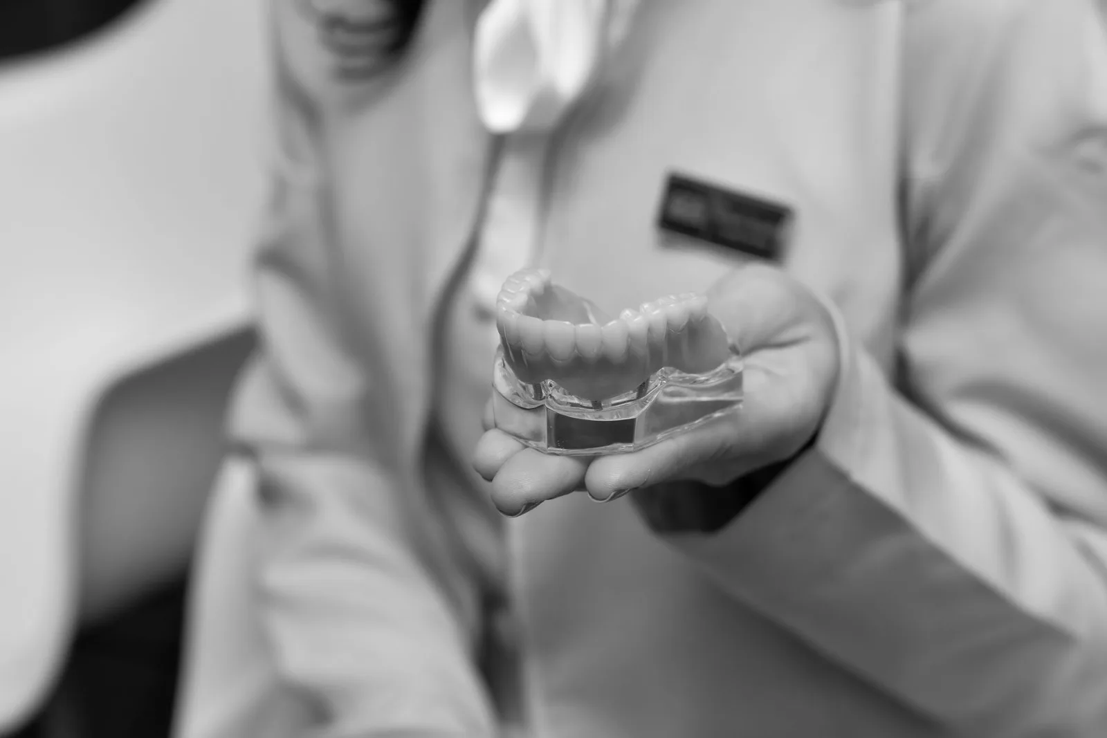 A dentist holding a dental implant model used to explain a treatment plan