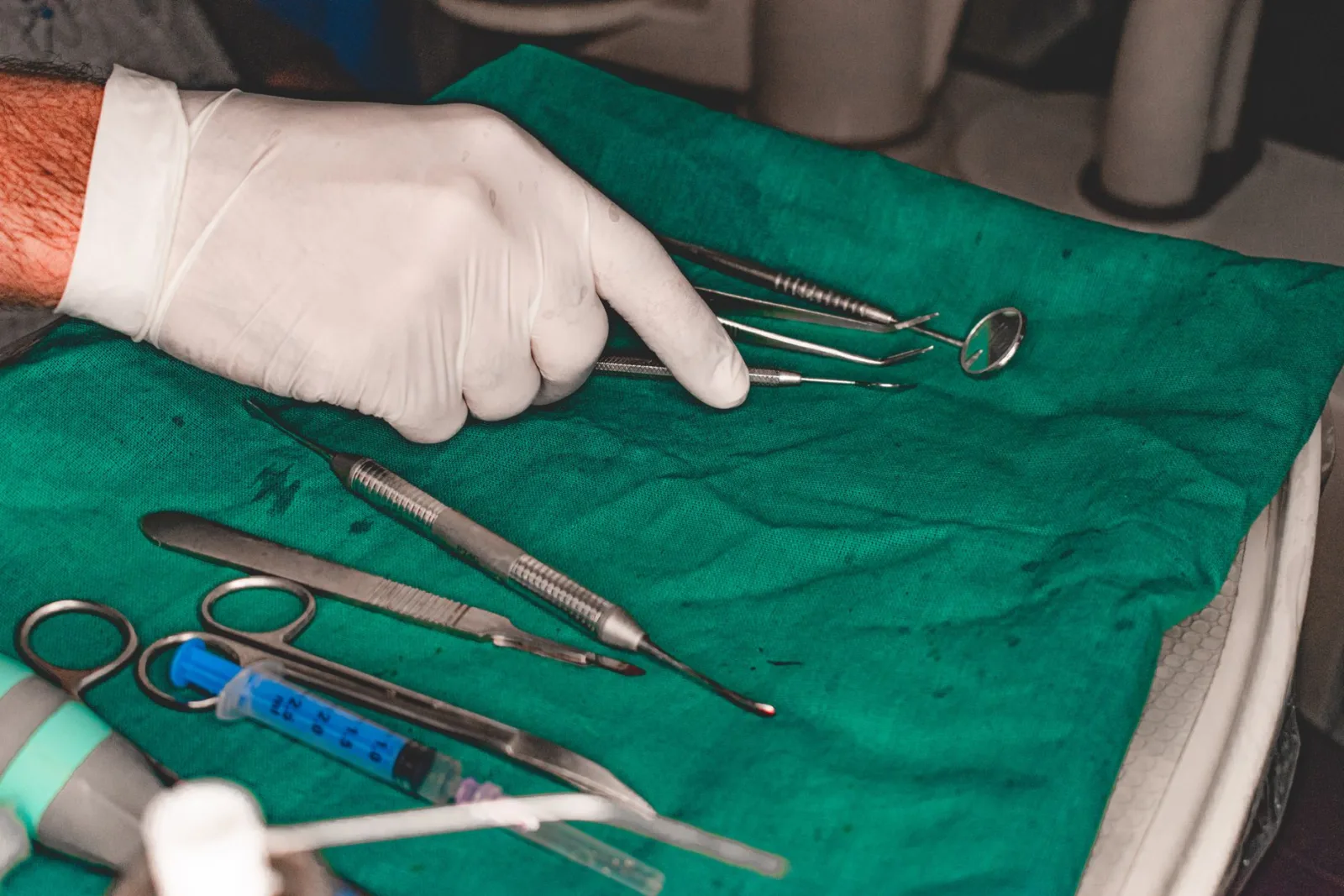 A gloved hand arranging sterile dental instruments for a surgical procedure