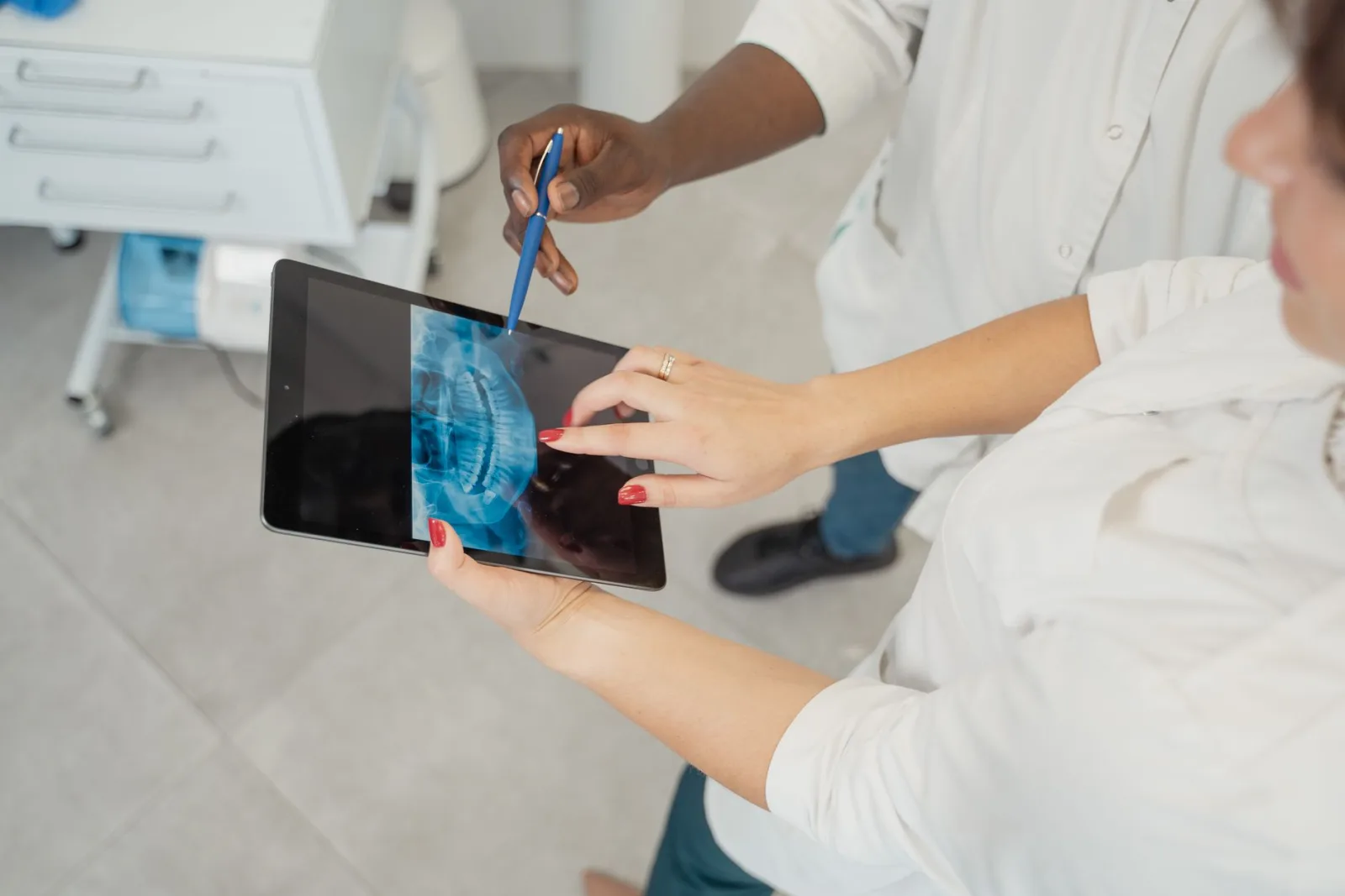 A dentist and a colleague reviewing a dental X-ray on a tablet in a clinic