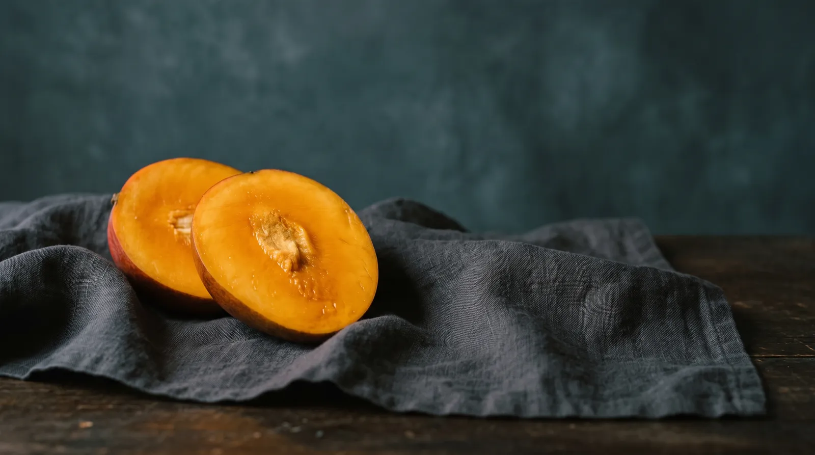 Still life: a halved mango on dark linen