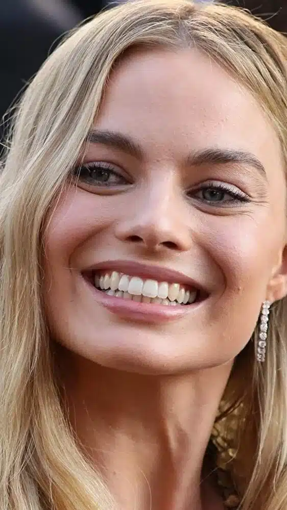 “Neutral studio portrait of Margot Robbie featuring soft, warm smile.”